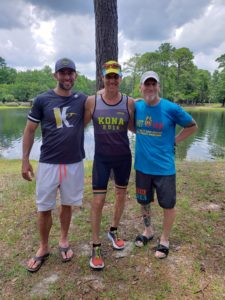 Three men standing by lake after finishing race